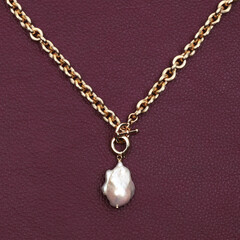 Fototapeta na wymiar Golden chain with white baroque pearl pendant