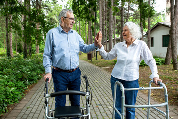 Elderly couple holding on to walking helper with one hand