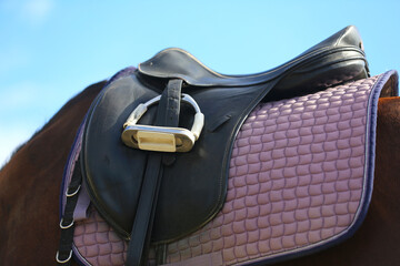 Photo of old leather saddle with stirrups