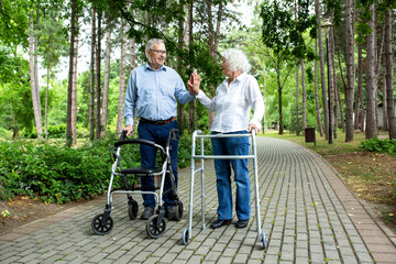 Elderly couple holding on to walking helper with one hand