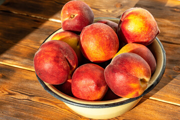 ripe peaches in an iron bowl on a wooden background in bright sunlight