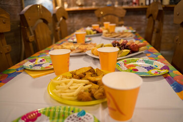 festive table with disposable cups, plates and food