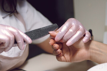 Obraz na płótnie Canvas women's hands in pink gloves do manicure 