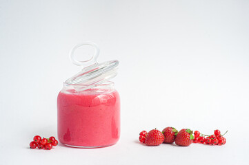 Jam of strawberries and red currants on a white background.