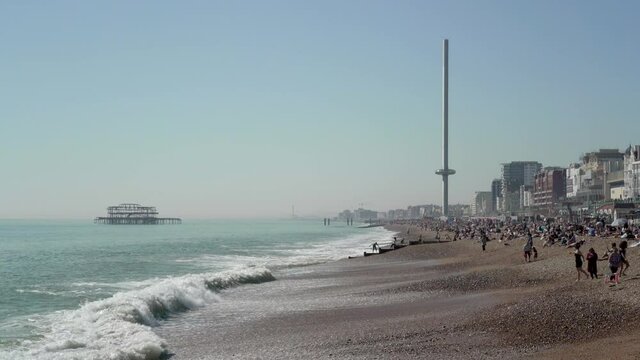 Brighton Beach full of tourirts in sun with i360 and paragliders, Brighton, East Sussex, England, United Kingdom