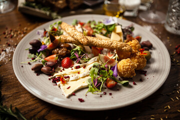 Cheese platter for two: Goat cheese cream, gorgonzola, camembert, grissini and fig jam. Delicious healthy Italian traditional food closeup served for lunch in modern gourmet cuisine restaurant