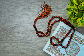 Holy Quran and rosary beads on wooden table 