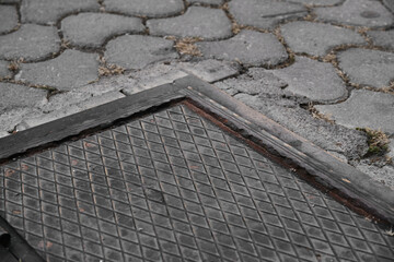 Rectangular black manhole cover and paving stones details