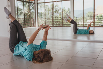 Young woman in a blue t-shirt is dancing in front of a mirror modern contemporary dancing in the dance hall