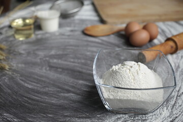 Flour, egg, olive oil, milk, wheat ears, kitchen tool on gray table background.