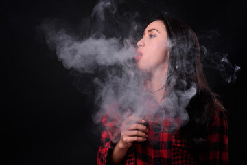 Young beautiful Asian woman vaping against black background