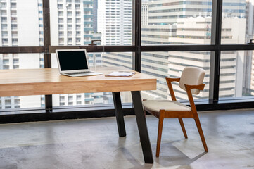 Laptop with business document on wooden desk and chair in modern office