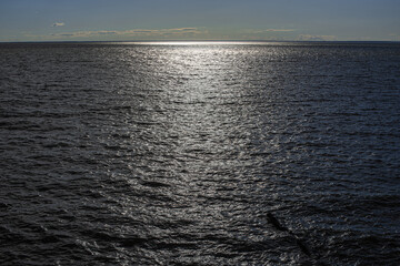 picturesque view of endless seascape with sunbeams reflecting on mirror water surface at sunny day