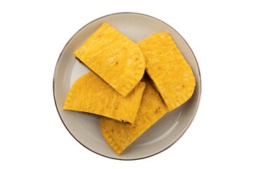 overhead view of cut up spicy Jamaican patties on a plate isolated on white