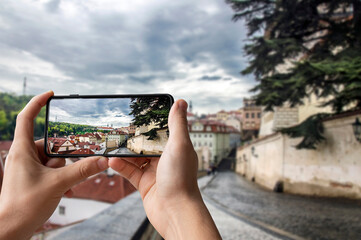 Tourist taking photo of view of street in Prague, Czech Republic. Man holding phone and taking picture of street with beautiful view on historic city center in Prague