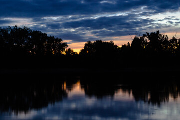 Fototapeta premium Sunset on the Volga river. View of one of the islands (the contours of trees against the sky) on the Volga from the shore during sunset.
