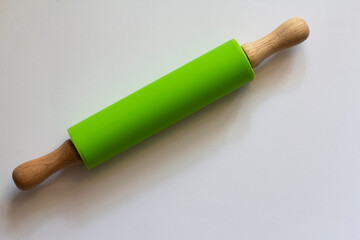 The green rolling pin with wooden handles isolated on a white background, kitchen utensils