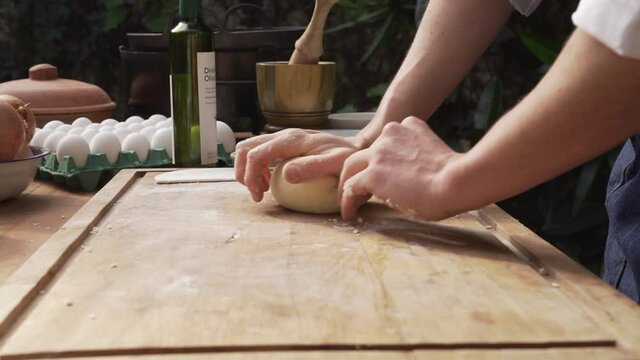 Manos del chef amasando en una tabla de madera, para preparar pan casero. Manos del chef amasando en una cocina al aire libre 