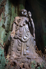 Obraz premium At an ancient sculpture of a standing Buddha. Tang Chong caves in the Marble mountains. Da Nang, Vietnam