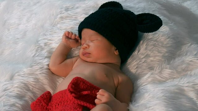 newborn baby in mouse costume sleeping on a fur bed