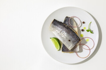 Salted herring with spices, lime slices and red onion rings on a white background. copy space. Flat lay.