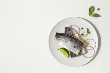 Salted herring with spices, lime slices and red onion rings on a white background. copy space. Flat lay.