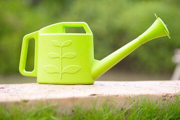 Portrait of green plastic watering can outdoors