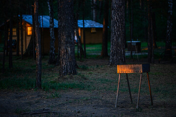 metal brazier near wooden cottages in forest at sunset 