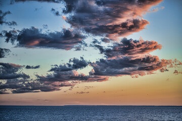 picturesque view of endless seascape with fluffy clouds in sky at sunset 