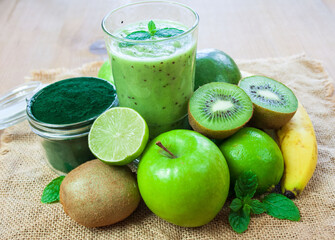 Zielone smoothie, owoce i spirulina na tkaninie z juty © Monika