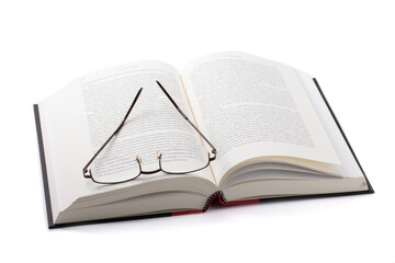 a pair of reading glasses lying on thick a hard cover book isolated on white