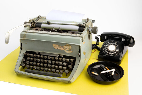 a before  digital reporter's workstation, manual typewrite, rotary phone and cigarettes in an ashtray on white