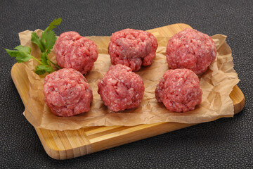 Raw meatball over wooden background