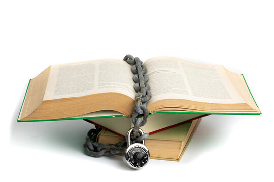 a lock and chain around an open old book illustrating the concept of censorship isolated on white