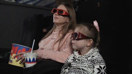Obraz premium Mother with her daughter are watching 3d film in cinema. Emotion - surprise