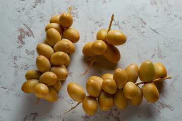 fresh dates fruit on textured white background , red and yellow fresh dates fruit in white plate