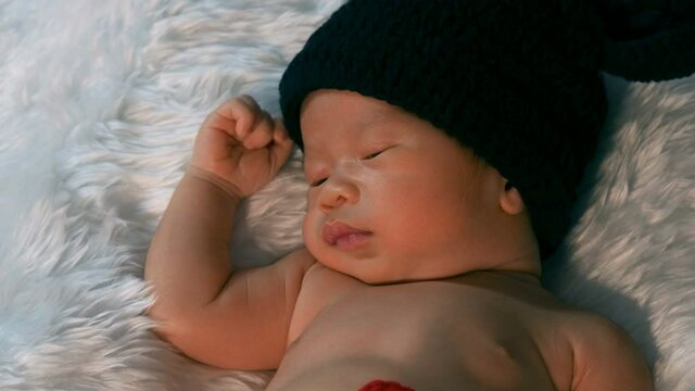 newborn baby in mouse costume sleeping on a fur bed