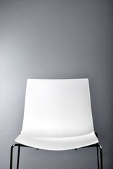 leerer weißer Stuhl vor grauem Hintergrund