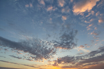 Sunset sky covered with orange puffy clouds in the evening.