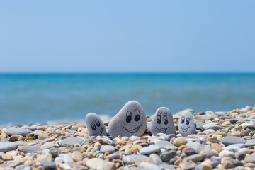 Group of stones with drawn faces in the sand. Father, mother, daughter and son. Concept of happy family.