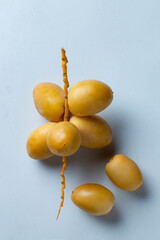 fresh dates fruit on textured white background , red and yellow fresh dates fruit in white plate