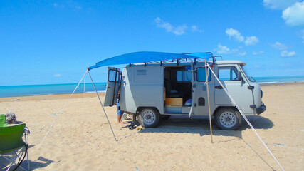 Fototapeta premium Camper on the beach with an awning from the sun. Vacation, clear, Sunny day. Camping.