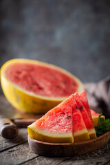 watermelon with yellow peel and watermelon slices in a wooden background.