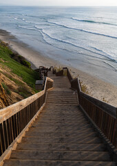 Gorgeous sunset background portrait photo of wooden steps leading down to the ocean during a calm, warm day in Cardiff by the Sea, California, north of San Diego on the Pacific Coast