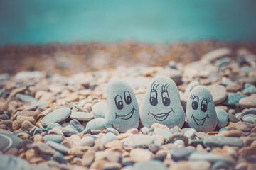 Pebbles with drawn faces in the sand. Father, mother and daughter. Family vocation concept