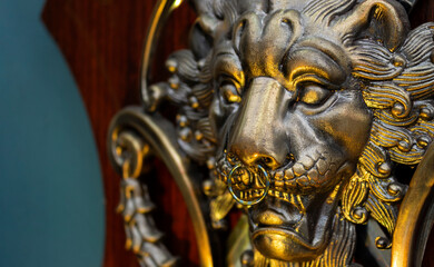 Fototapeta na wymiar Close up to a golden Iron Lion shiled iluminated with yellow light and a septum piercing jewel . Interior design, ornaments, tattoo and piercing concept