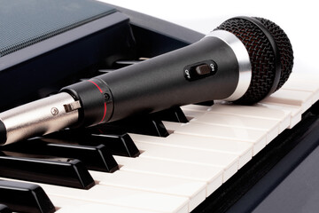 a vocalist microphone lying on an electronic piano keyboard on a white background