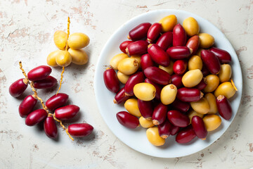fresh date fruits in white plate , red and yellow fresh date fruits on white background