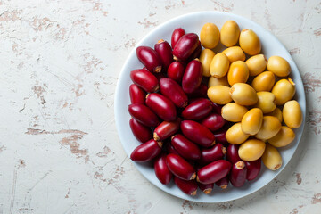 fresh date fruits in white plate , red and yellow fresh date fruits on white background