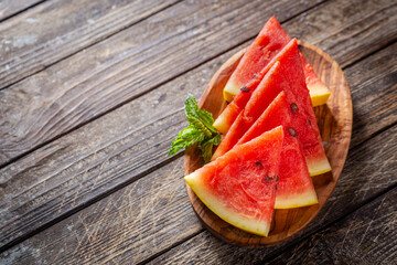 watermelon with yellow peel and watermelon slices in a wooden background.